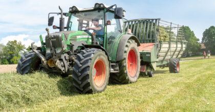 Ein Mann sammelt mit einem Traktor die gemähten Futterpflanzen.