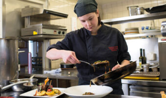 Eine Köchin richtet einen Teller an.