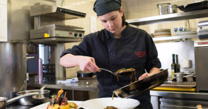 Eine Köchin richtet einen Teller an.