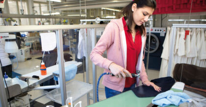 Eine Frau reinigt in einer Wäscherei ein Textilstück.