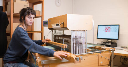 Eine Frau webt Stoffe mit einem Handwebstuhl.