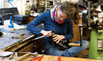 Eine Frau befestigt die Sohle an einem Stiefel.