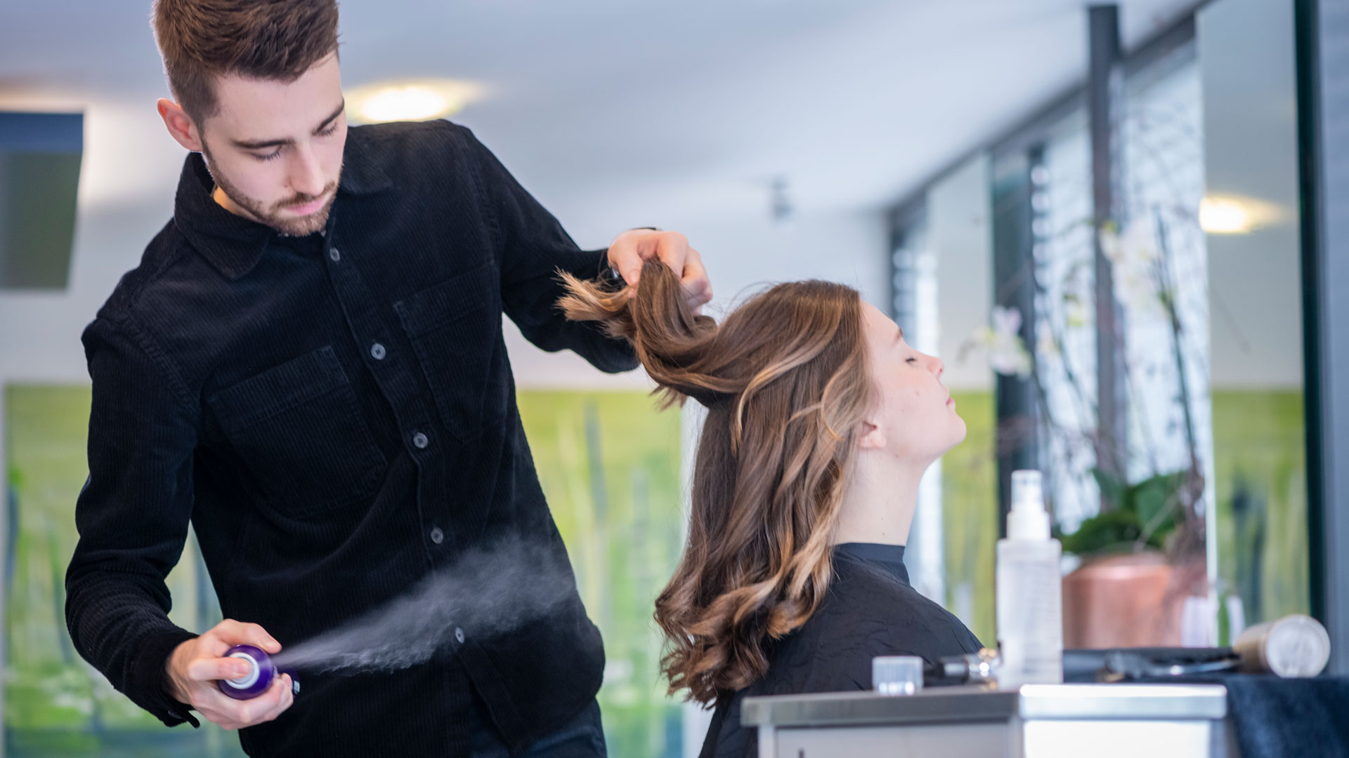 Ein Mann frisiert einer Frau die Haare.