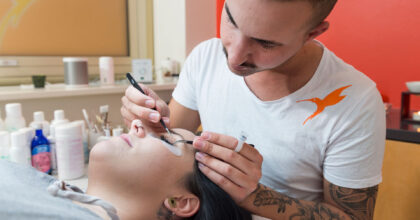 Ein Mann führt bei einer Frau eine Gesichtsbehandlung durch.