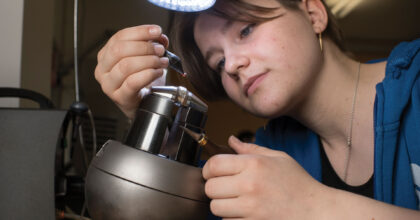 Eine Frau platziert in einem Atelier Edelsteine auf einem Schmuckstück.