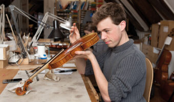 Ein Mann führt in einem Atelier Wartungsarbeiten an einer Geige durch.