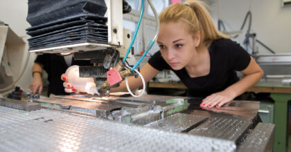 Eine Frau benutzt eine Maschine um ein Objekt zu gravieren.