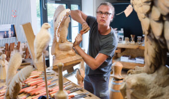 Ein Mann in einem Atelier schnitzt eine Holzskulptur.