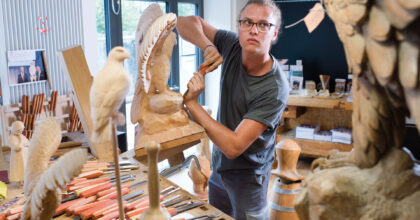 Ein Mann in einem Atelier schnitzt eine Holzskulptur.