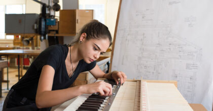 Eine Frau befestigt eine Schraubmutter an einer Orgel.