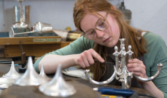 Eine Frau schraubt ein silbernes Objekt zusammen.