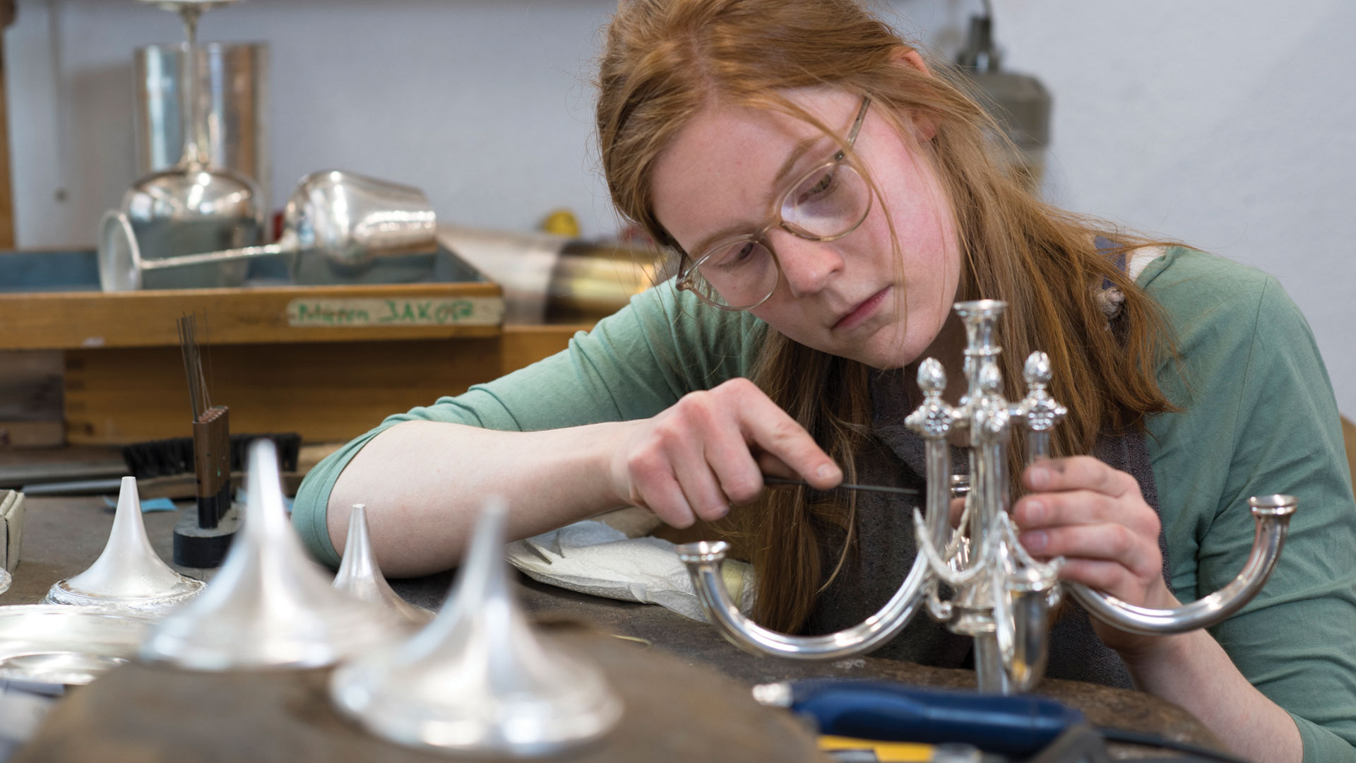 Eine Frau schraubt ein silbernes Objekt zusammen.