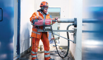 Eine Frau führt Bohrarbeiten an einer Betonwand durch.