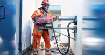 Eine Frau führt Bohrarbeiten an einer Betonwand durch.