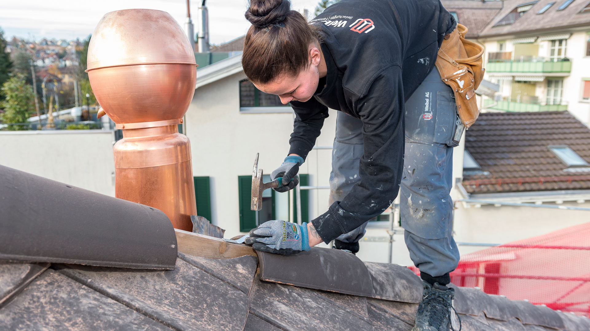 Eine Frau montiert Dachziegel auf dem Dach eines Hauses.