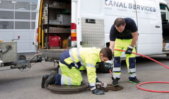 Zwei Männer inspizieren einen Abwasserschacht mit Spezialgerät.