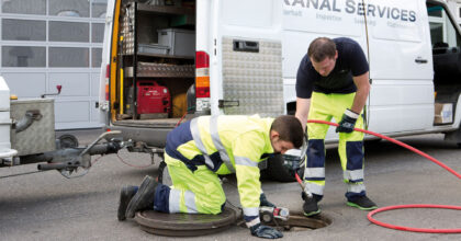 Zwei Männer inspizieren einen Abwasserschacht mit Spezialgerät.