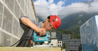 Ein Mann schneidet auf der Baustelle ein Holzstück mit einer Stichsäge.