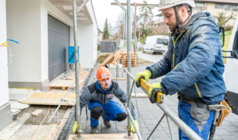 Zwei Männer überprüfen mit einer Wasserwaage ob das Baugerüst waagrecht steht.