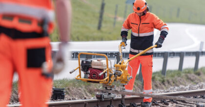 Ein Mann befestigt das Gleis mit Schwellenschrauben.