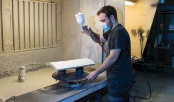 Ein Mann lackiert ein Keramikprodukt mit einer Spritzpistole.