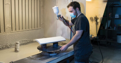 Ein Mann lackiert ein Keramikprodukt mit einer Spritzpistole.