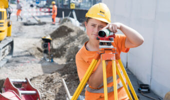 Eine Frau bedient auf einer Baustelle einen Laserentfernungsmesser.