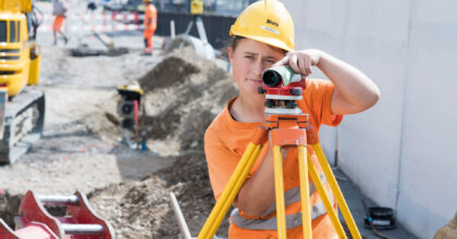 Eine Frau bedient auf einer Baustelle einen Laserentfernungsmesser.
