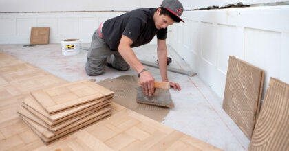 Ein Mann verlegt in einem Haus Parkettboden.