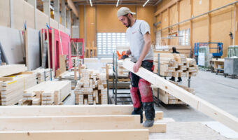 In einer Werkhalle schleift ein Mann ein Holzbrett.