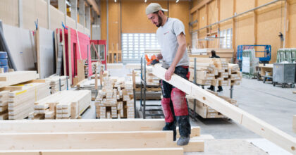 In einer Werkhalle schleift ein Mann ein Holzbrett.