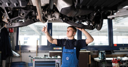 Ein Mann führt in einer Autowerkstatt Wartungsarbeiten an einem Fahrzeug durch.