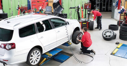 Ein Mann in einer Garage wechselt das Rad eines Fahrzeugs aus.