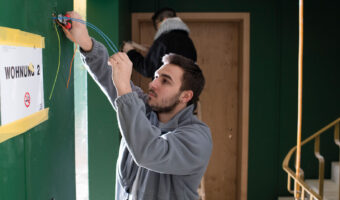 Ein Mann verlegt Kabel im Treppenhaus eines Gebäudes.