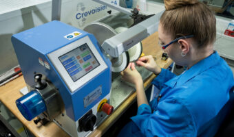 Eine Frau poliert mit einer Maschine ein Uhrenteil.