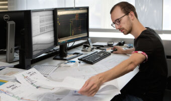 Ein Mann schaut sich sowohl analoge als auch digitale Baupläne an.