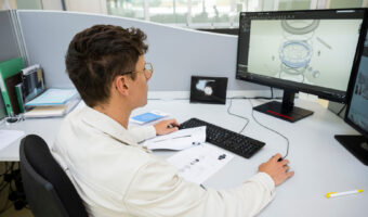 Ein Mann schaut sich am Bildschirm 3D-Entwürfe einer Uhr an.