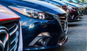 Kühlerhauben mehrerer hintereinander geparkten Autos im Ausschnitt.