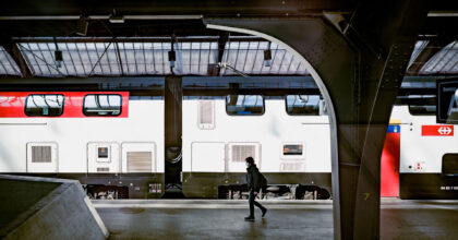 Person auf einem Perron am Bahnhof vor einem stehenden Zug.