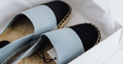Offene Espadrilles liegen auf Seidenpapier in einem Schuhkarton.