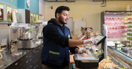 Ein Mann wägt Käse an der Käsetheke.