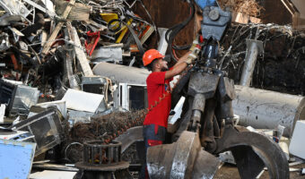 Ein Mann in einer Recyclinghalle wartet eine Greifvorrichtung.