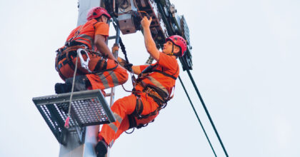 Zwei Männer führen Wartungsarbeiten an der Stütze einer Seilbahn durch.