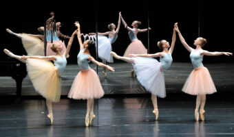 Vier Ballerinas tanzen in Zweiergruppen vor einem Spiegel.