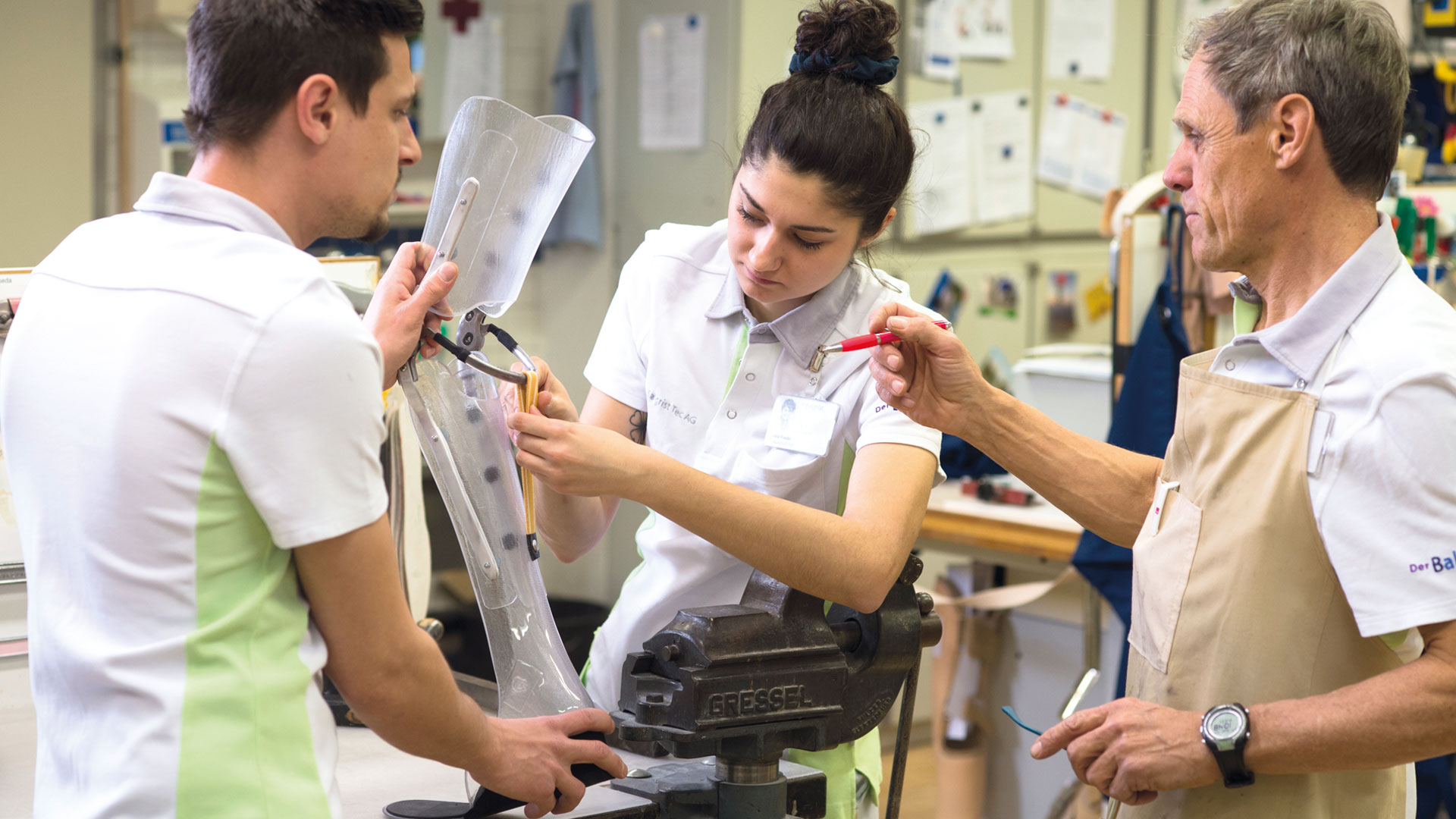 Eine Frau und zwei Männer fertigen eine Beinprothese an.