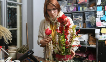 Eine Frau steht an einem Tisch und arrangiert ein Gesteck.