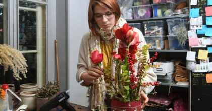 Eine Frau steht an einem Tisch und arrangiert ein Gesteck.