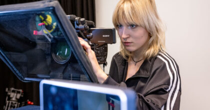 Eine Frau stellt eine Filmkamera ein.