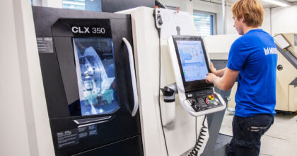 Ein Mann steht vor einer Maschine und tippt etwas auf einem Touchscreen.