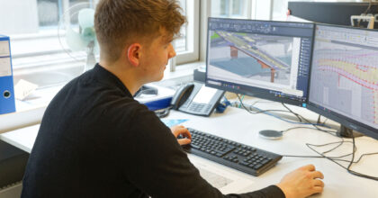 Ein Mann schaut sich an zwei Computerbildschirmen Pläne einer Brücke an.